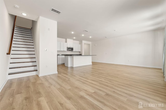 unfurnished living room featuring visible vents, recessed lighting, baseboards, and light wood-type flooring