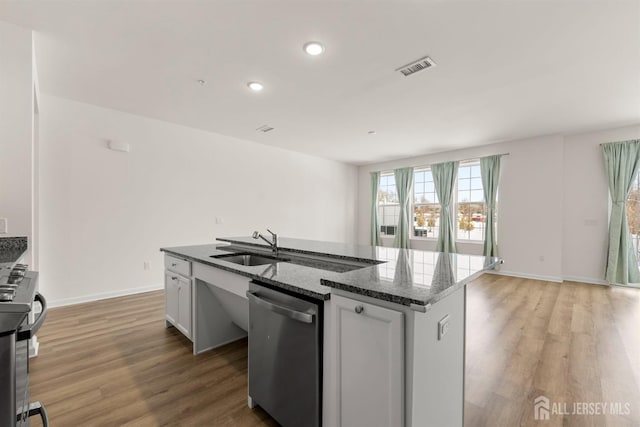 kitchen with visible vents, light wood-style floors, an island with sink, a sink, and appliances with stainless steel finishes