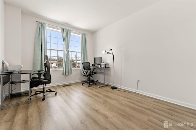 home office with baseboards and wood finished floors