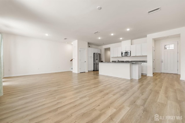 unfurnished living room with visible vents, baseboards, stairway, recessed lighting, and light wood-type flooring