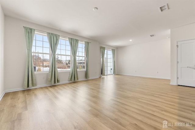 empty room featuring recessed lighting, baseboards, light wood finished floors, and visible vents