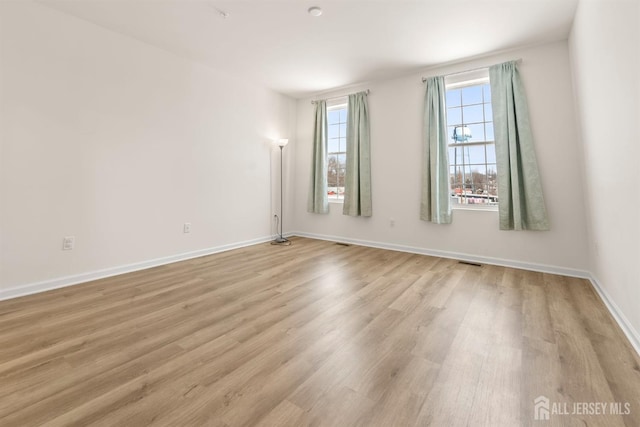 empty room featuring baseboards, visible vents, and wood finished floors