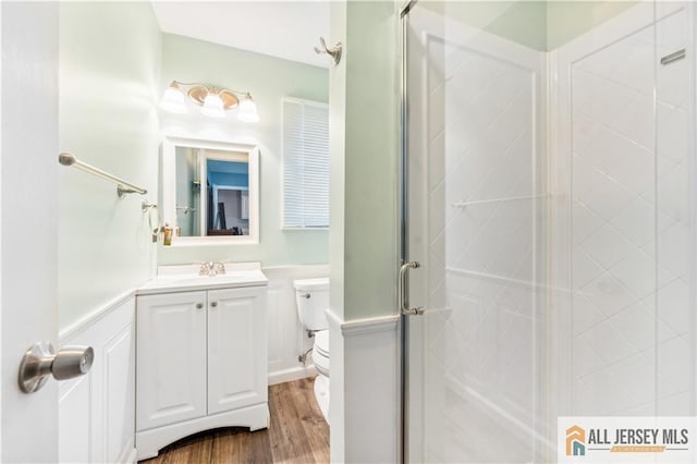 bathroom featuring wood-type flooring, vanity, toilet, and a shower with door