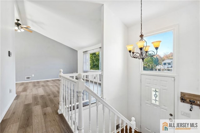 entrance foyer with vaulted ceiling, ceiling fan with notable chandelier, and hardwood / wood-style flooring