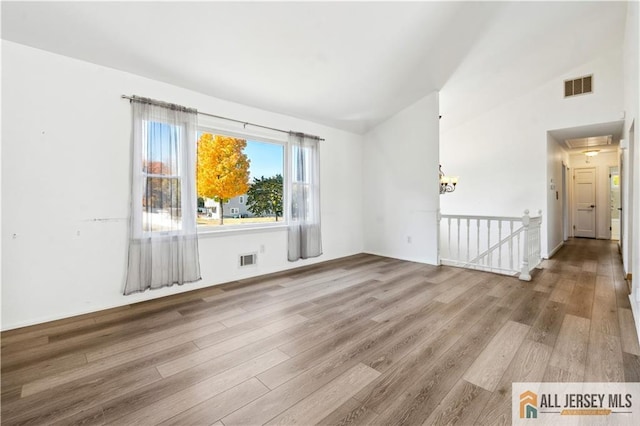 unfurnished room featuring wood-type flooring and lofted ceiling