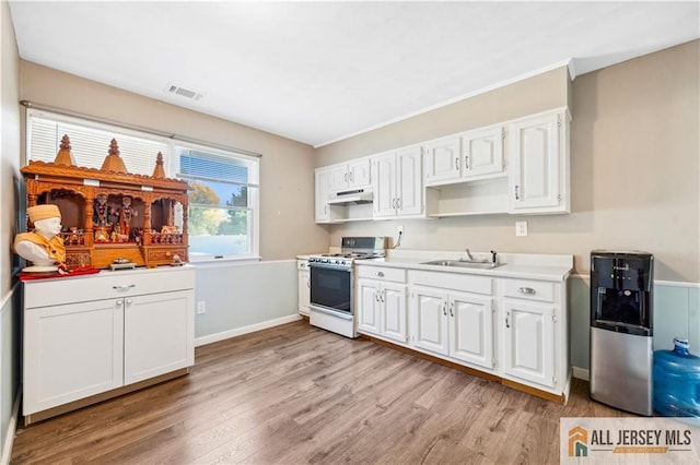 kitchen with white cabinets, sink, light wood-type flooring, and white gas range oven