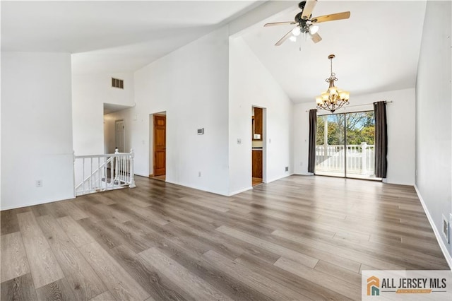 unfurnished living room with high vaulted ceiling, ceiling fan with notable chandelier, and light wood-type flooring