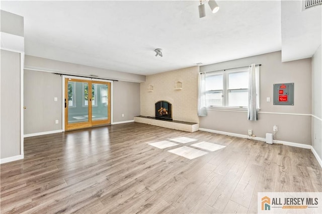 unfurnished living room with wood-type flooring and a brick fireplace