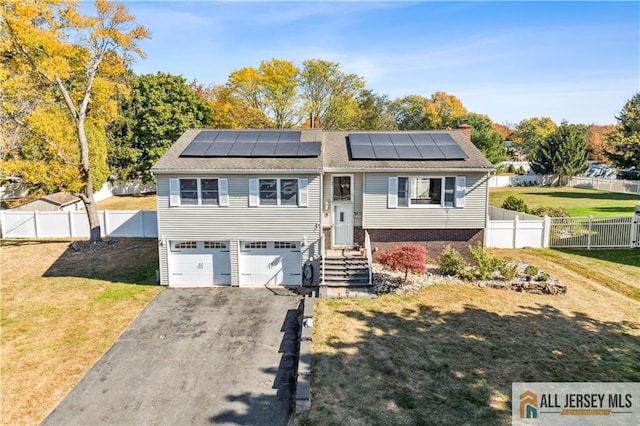 split foyer home with a garage, a front yard, and solar panels