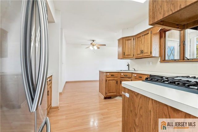 kitchen featuring ceiling fan, light wood-type flooring, sink, and stainless steel refrigerator