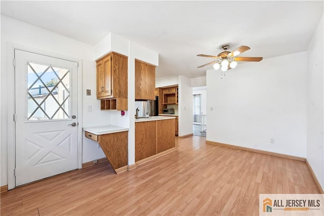 kitchen with ceiling fan, light hardwood / wood-style floors, kitchen peninsula, and sink