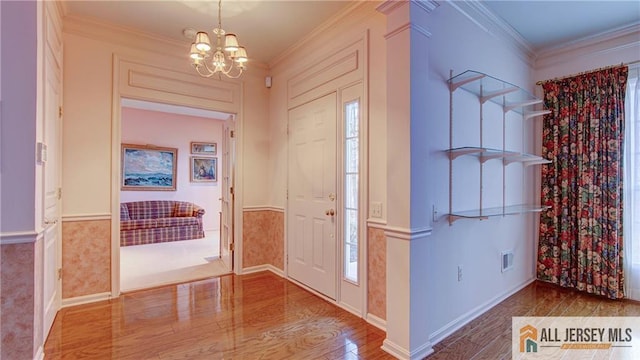 foyer with visible vents, ornamental molding, a notable chandelier, and wood finished floors