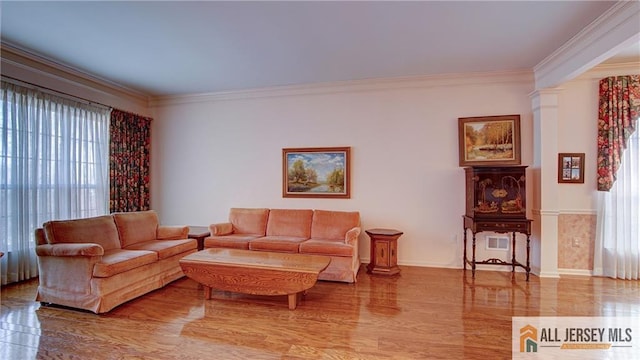 living area with crown molding, baseboards, wood finished floors, and ornate columns