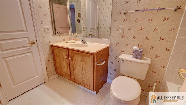 bathroom with wallpapered walls, toilet, vanity, baseboards, and tile patterned floors