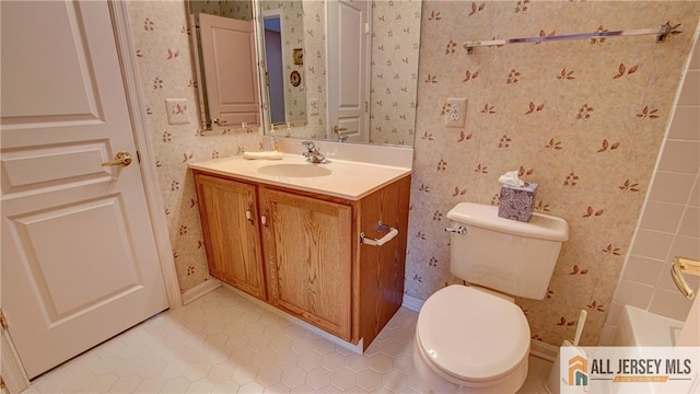 bathroom with tile patterned floors, toilet, vanity, baseboards, and wallpapered walls