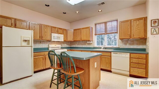 kitchen with light floors, visible vents, a kitchen island, a sink, and white appliances