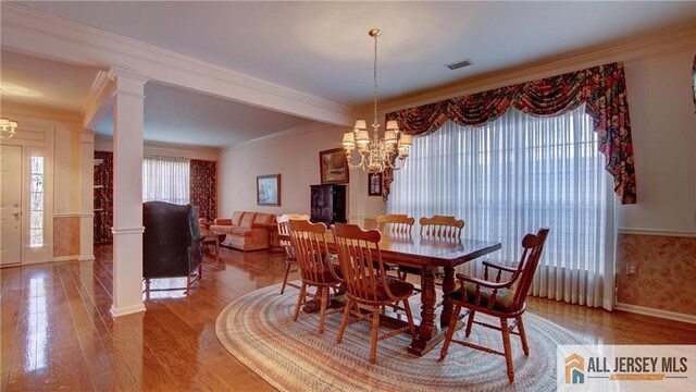 dining space featuring a chandelier, a healthy amount of sunlight, and decorative columns