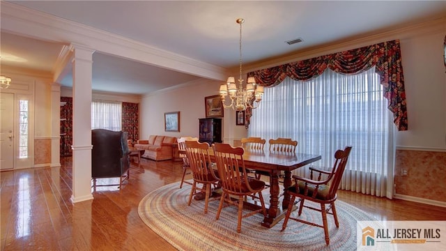 dining room with a wealth of natural light, wood finished floors, a chandelier, and crown molding