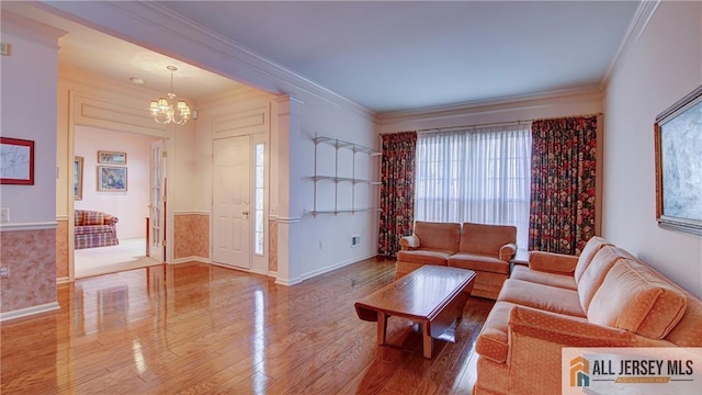 living area featuring ornamental molding, wood finished floors, baseboards, and an inviting chandelier