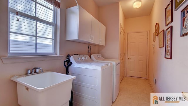 clothes washing area featuring separate washer and dryer, cabinet space, and a sink