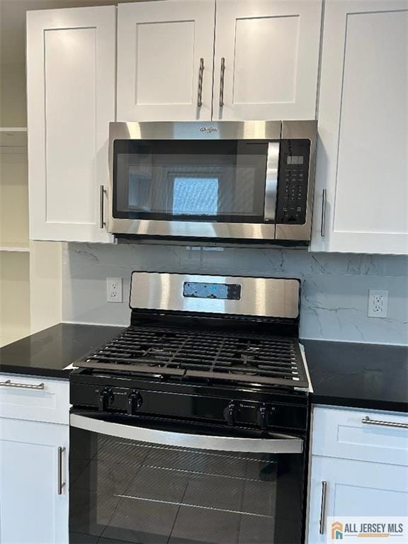 23 June St, South River, NJ 08882 - kitchen featuring stainless steel appliances, white cabinets, decorative backsplash, and dark countertops