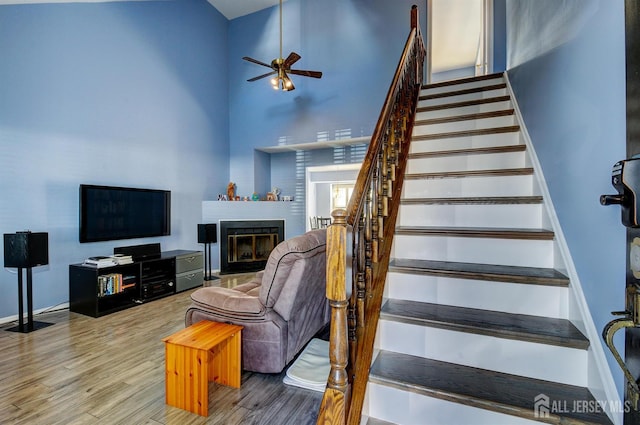 277 Edgeware Ct, Franklin, NJ 08873 - stairway with wood finished floors, ceiling fan, a towering ceiling, and a glass covered fireplace