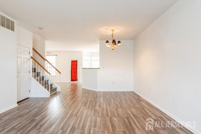 unfurnished room featuring hardwood / wood-style flooring and a notable chandelier