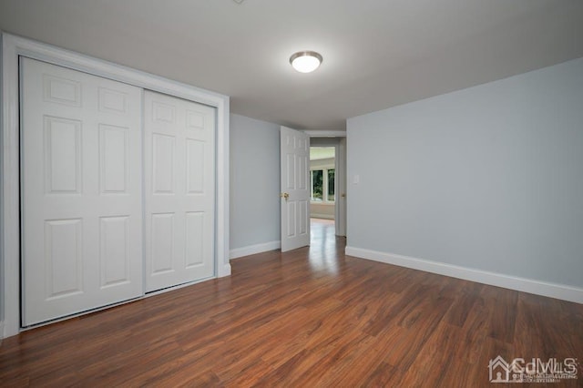 unfurnished bedroom featuring dark wood-type flooring and a closet