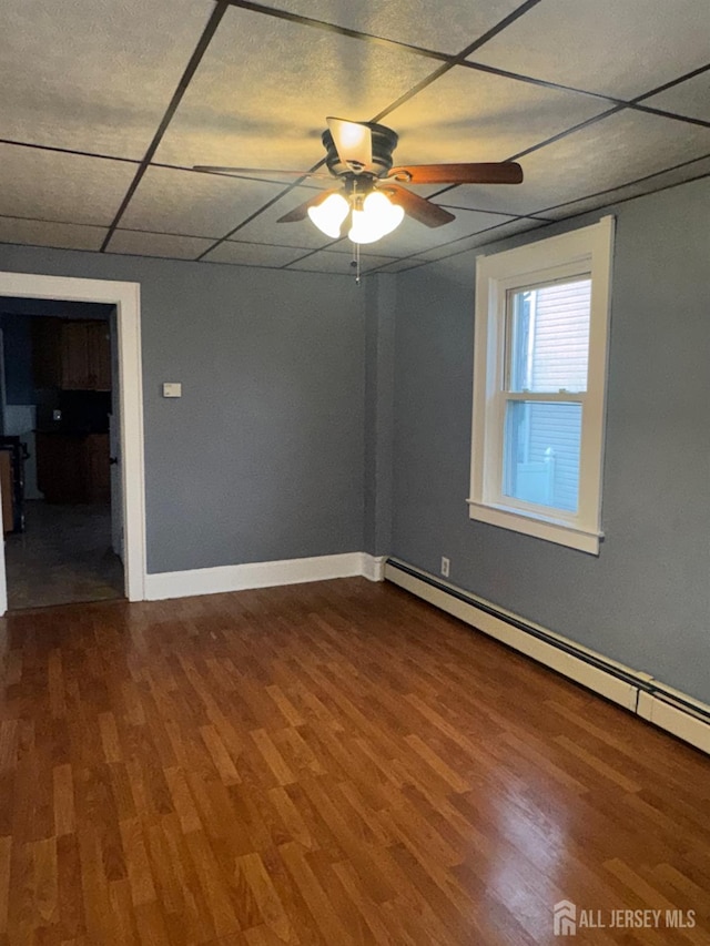 74 Spring St, Woodbridge Proper, NJ 07095 - unfurnished room featuring a baseboard heating unit, wood finished floors, a ceiling fan, and a drop ceiling