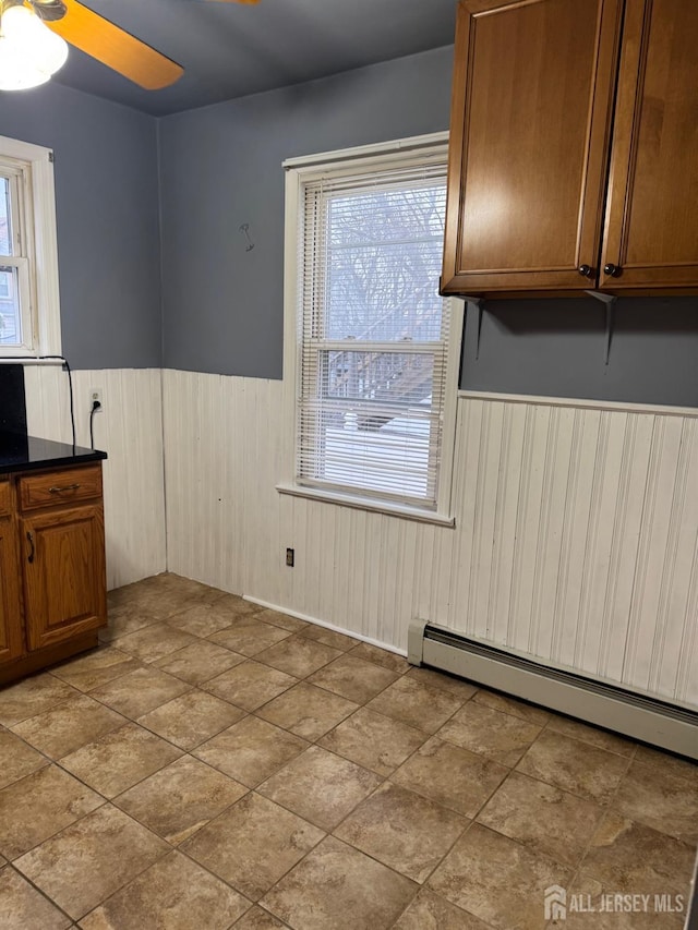74 Spring St, Woodbridge Proper, NJ 07095 - unfurnished dining area featuring a wainscoted wall, plenty of natural light, a ceiling fan, baseboard heating, and wood walls