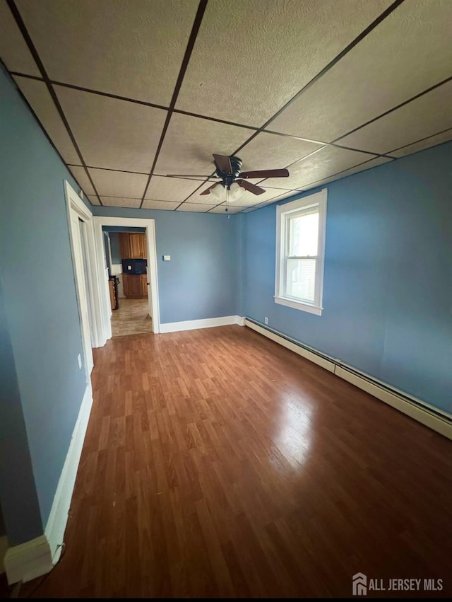 74 Spring St, Woodbridge Proper, NJ 07095 - unfurnished room featuring a ceiling fan, a paneled ceiling, wood finished floors, and a baseboard heating unit