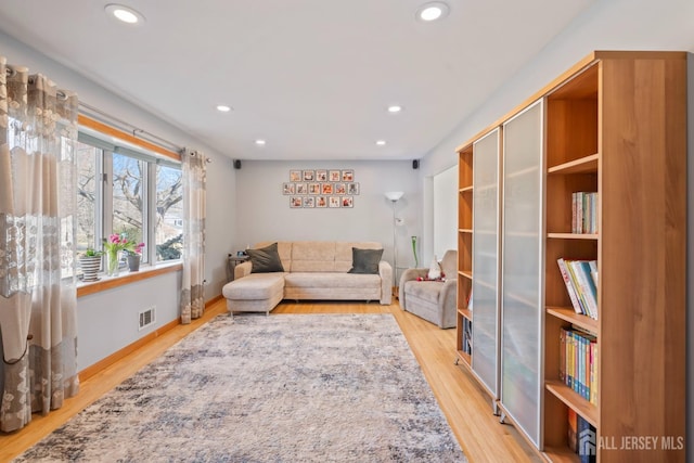 living area with light wood-style floors, recessed lighting, visible vents, and baseboards