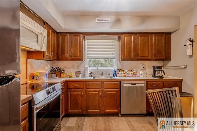 64 Netherwood Cir, Edison, NJ 08820 - kitchen with appliances with stainless steel finishes, light wood finished floors, decorative backsplash, and brown cabinets