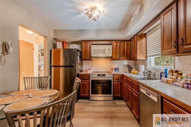 64 Netherwood Cir, Edison, NJ 08820 - kitchen with stainless steel appliances, light wood-style flooring, backsplash, and brown cabinetry