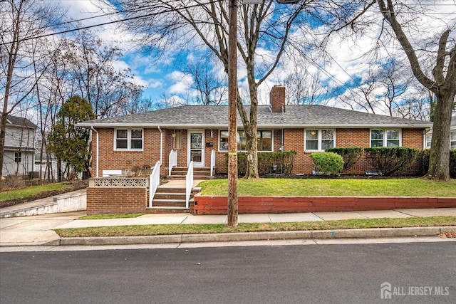 ranch-style home featuring brick siding, a chimney, and a front lawn