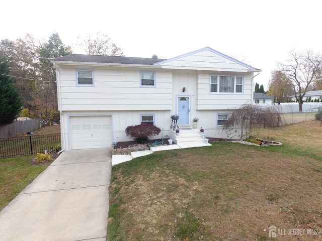 split foyer home featuring a front yard, concrete driveway, fence, and an attached garage