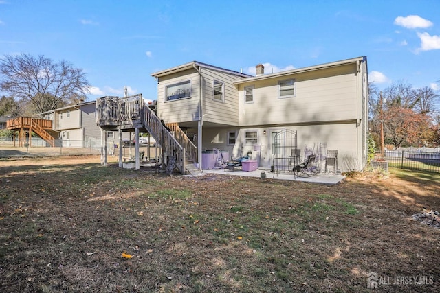 rear view of house with a wooden deck, a patio, stairs, fence, and a yard