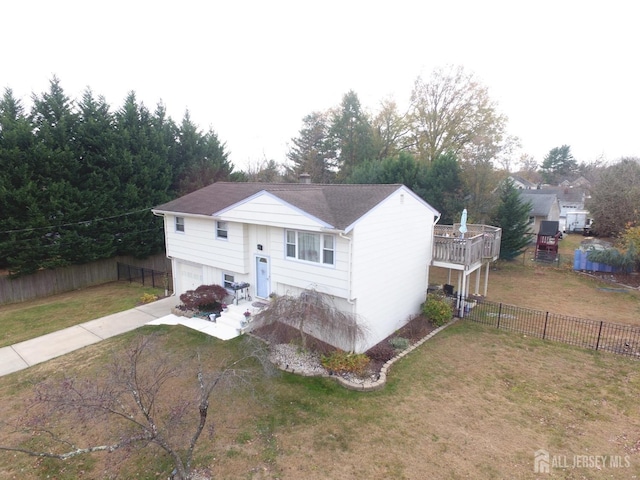 view of front of home with concrete driveway, fence, a front lawn, and an attached garage