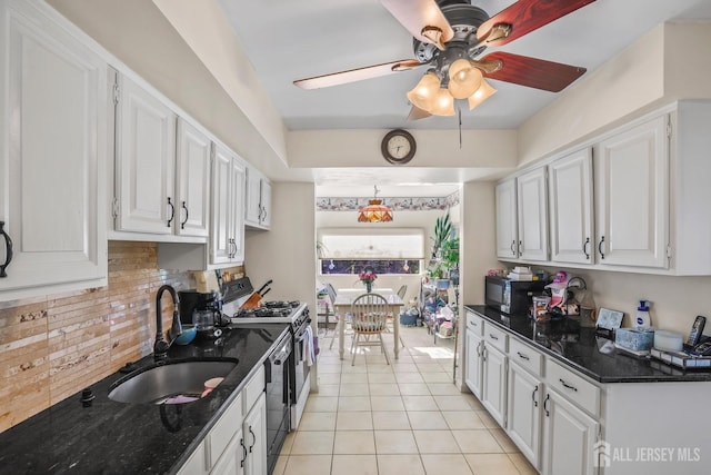 kitchen with gas range oven, white cabinetry, backsplash, and a sink