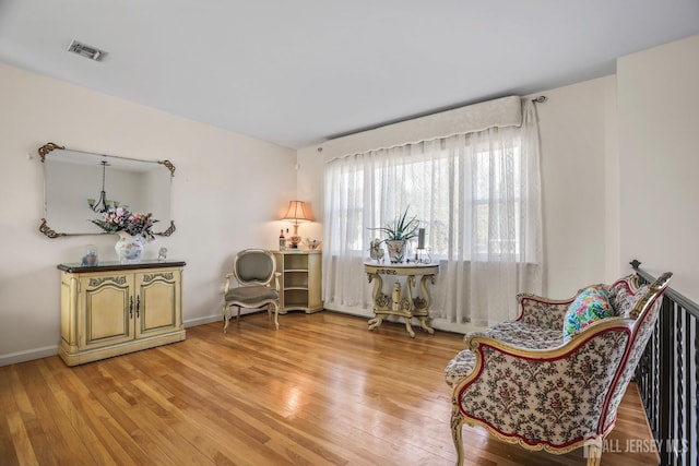 living area featuring light wood-style flooring, visible vents, and baseboards