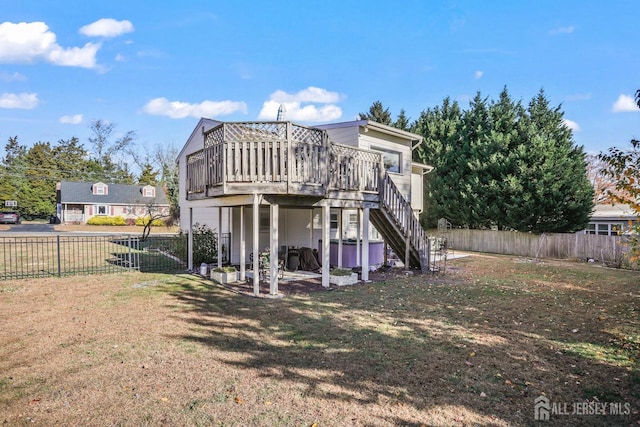 rear view of house with a fenced backyard, stairway, a lawn, and a wooden deck