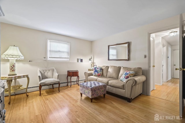 living area with wood-type flooring and a baseboard heating unit