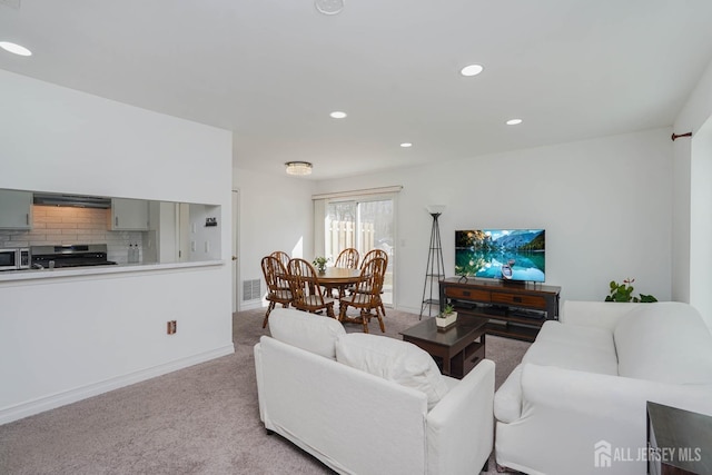 living room featuring recessed lighting, light colored carpet, visible vents, and baseboards