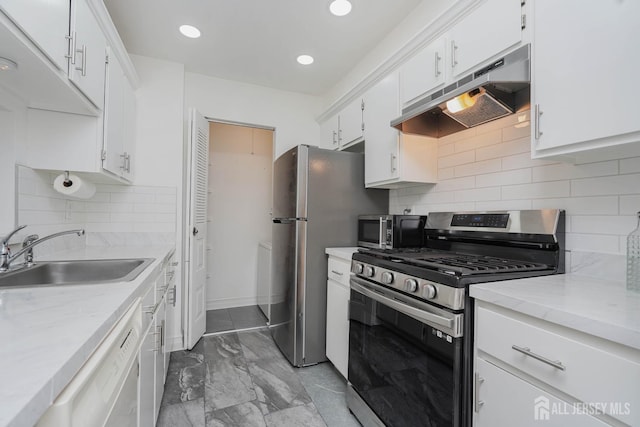 kitchen with marble finish floor, stainless steel appliances, under cabinet range hood, white cabinetry, and a sink