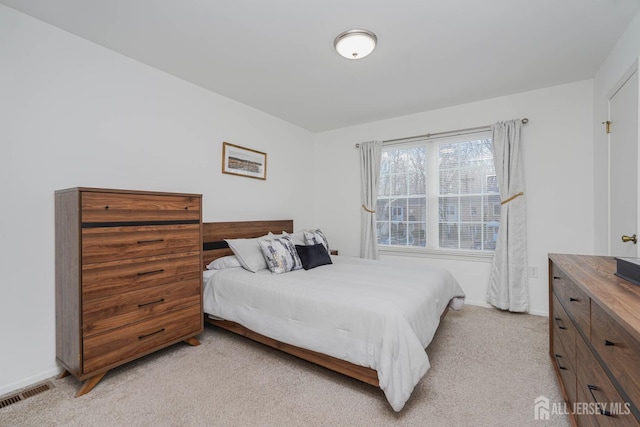 bedroom featuring baseboards, visible vents, and light colored carpet