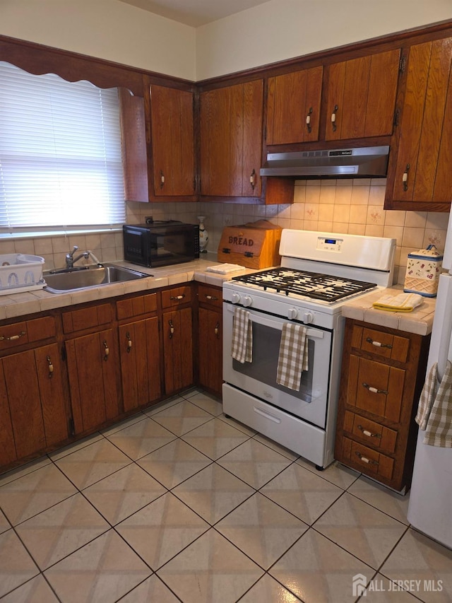 410 Harvard St, Piscataway, NJ 08854 - kitchen with white range with gas cooktop, under cabinet range hood, black microwave, tile countertops, and decorative backsplash