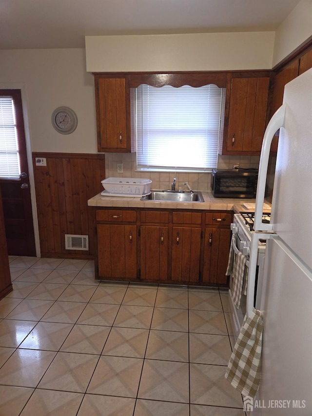 410 Harvard St, Piscataway, NJ 08854 - kitchen with freestanding refrigerator, light countertops, a wainscoted wall, decorative backsplash, and brown cabinetry