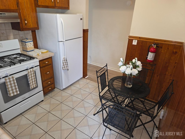 410 Harvard St, Piscataway, NJ 08854 - kitchen with white appliances, under cabinet range hood, brown cabinetry, light countertops, and backsplash