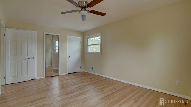 unfurnished bedroom with light wood finished floors, baseboards, and multiple closets
