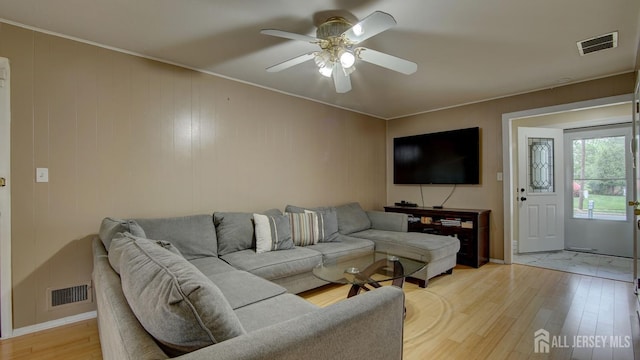 living area featuring light wood-style flooring, a ceiling fan, crown molding, and baseboards